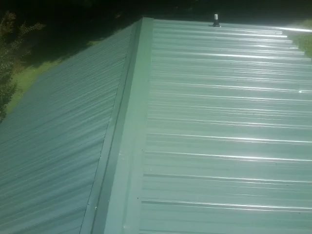 New green metal panels meeting at the ridge of a roof — Flat Roof Repair work by our crew in Londonderry