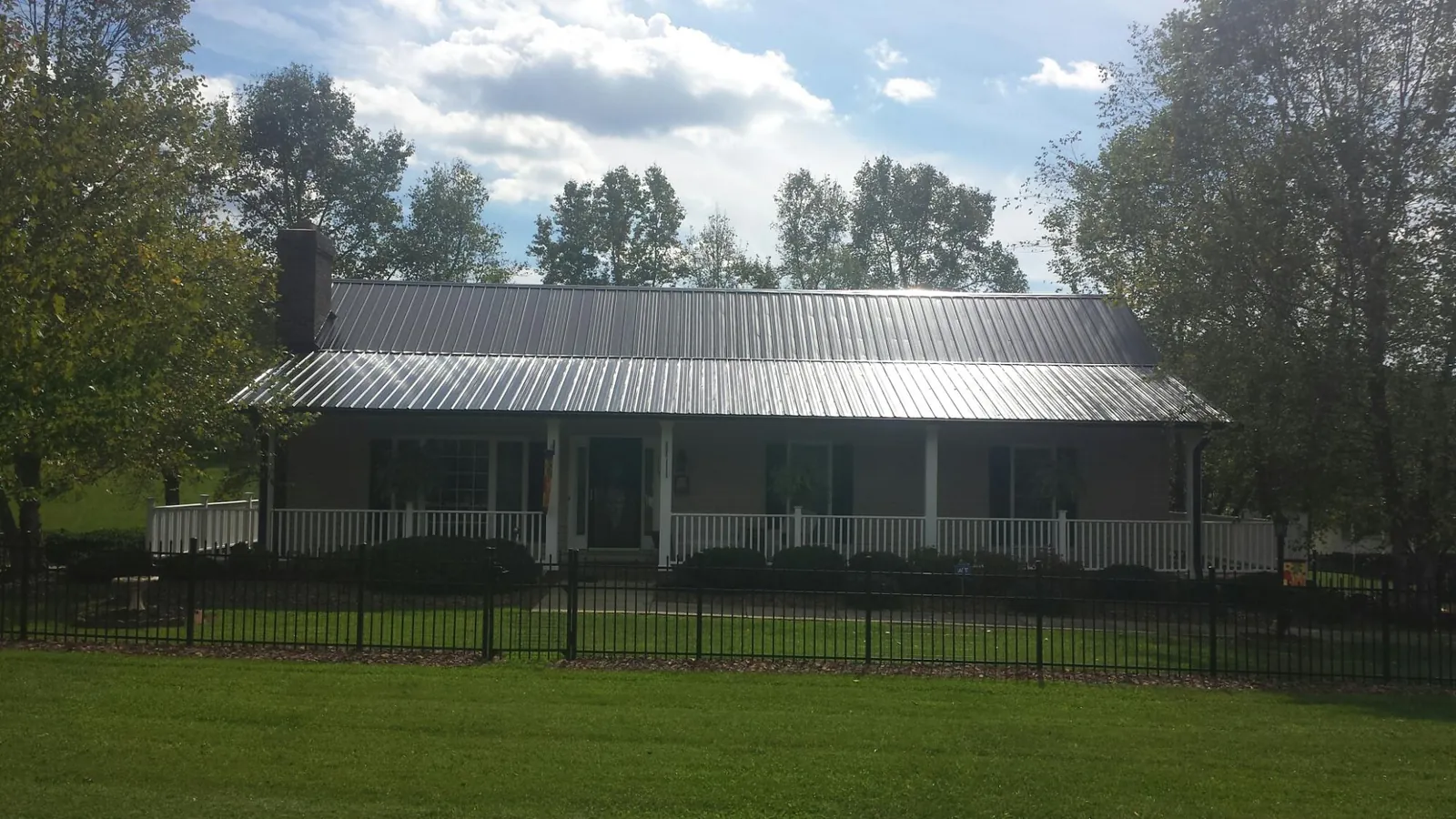 Gray metal roof on a brick ranch with a full width front porch — Gutter Guard Installation work by our crew in Londonderry