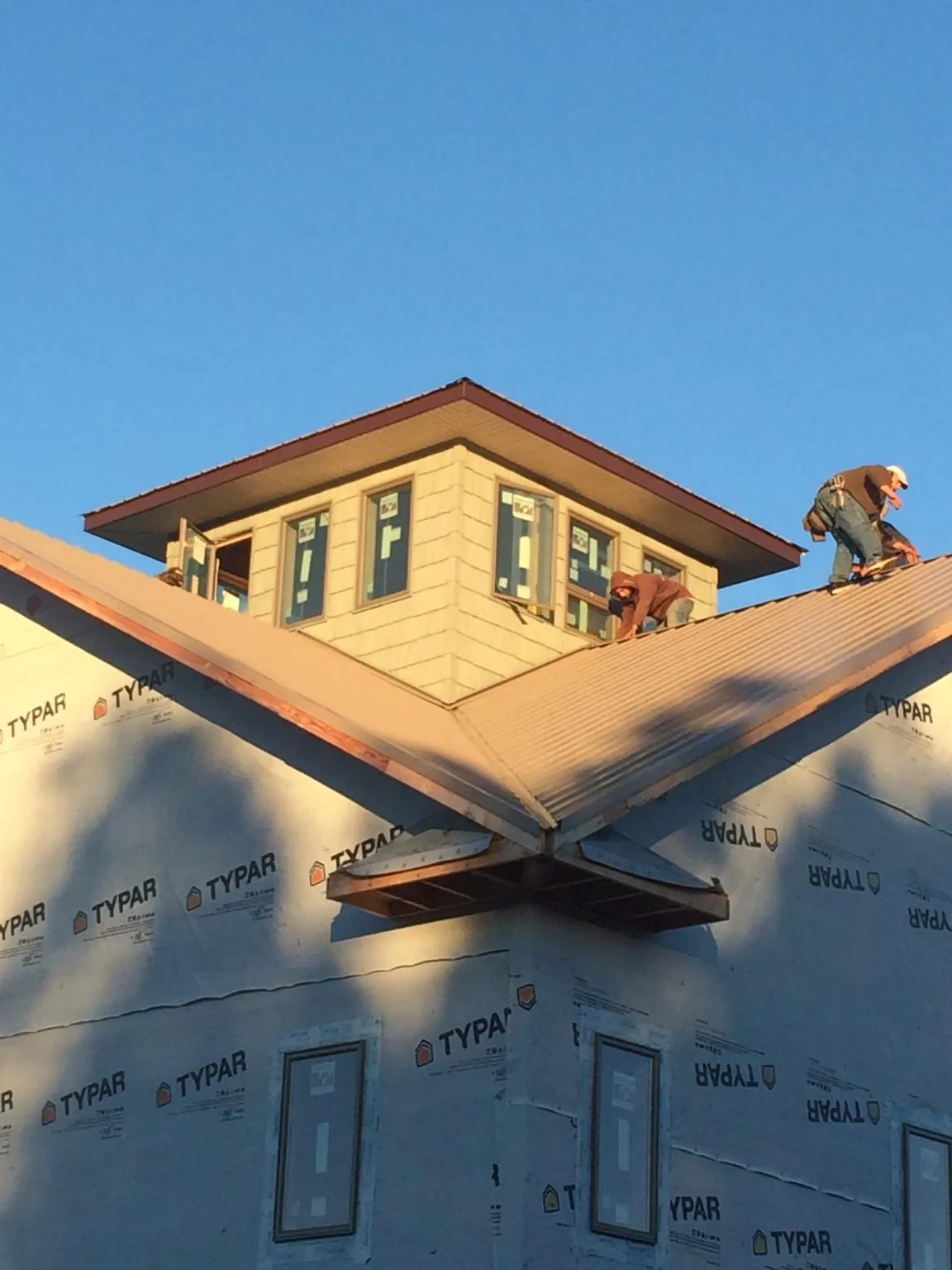 Roofers working around a rooftop cupola on a new metal roof at sunset — Roof Waterproofing in Londonderry by Roofing Brothers